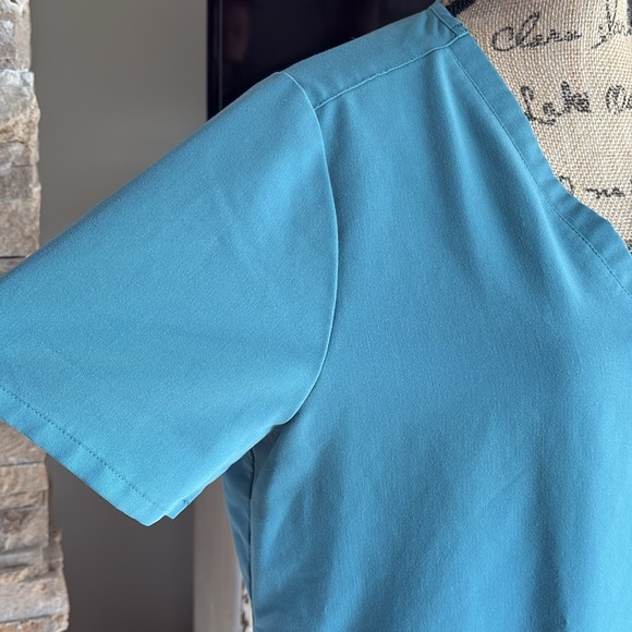 FIGS v-neck short sleeve two front pocket scrub shirt in a blue green color - Picture 3 of 16